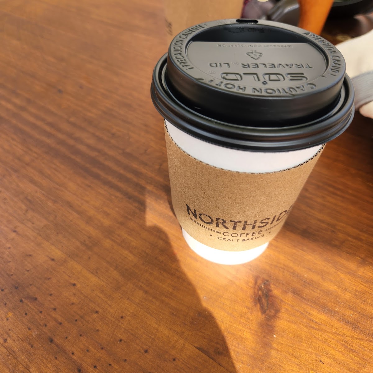 A branded Northside Coffee cup on a warm wood table inside the café